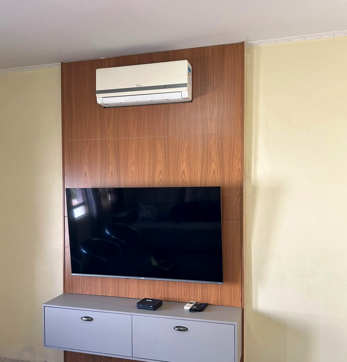 Painel de TV amadeirado com rack suspenso claro na sala